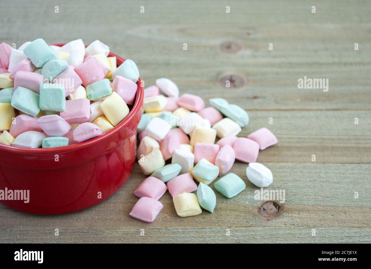 un petit bol rouge de bonbons couleur pastel qui déborde sur une table en  bois avec espace de copie Photo Stock - Alamy