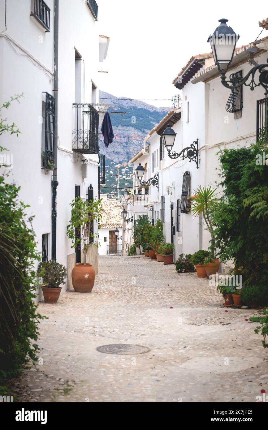 Allée avec pots de fleurs le long des maisons blanches avec vue sur les montagnes dans la vieille ville d'Altea, Costa Blanca, Espagne Banque D'Images