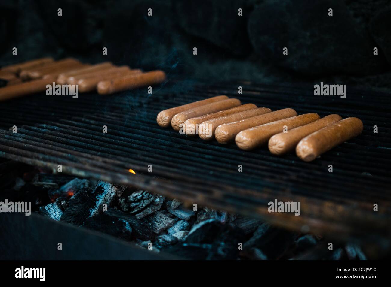 Beaucoup de hot dogs étant cuits dans un grill avec un arrière-plan flou Banque D'Images