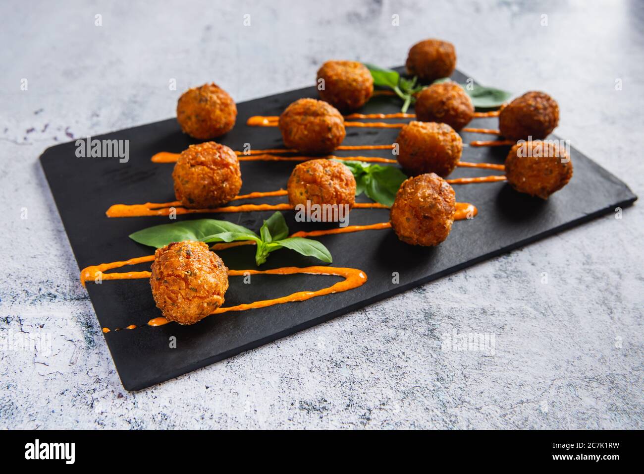 Boulettes de pommes de terre frites ou croquettes avec sauce à l'orange et salade verte. Mise au point sélective Banque D'Images