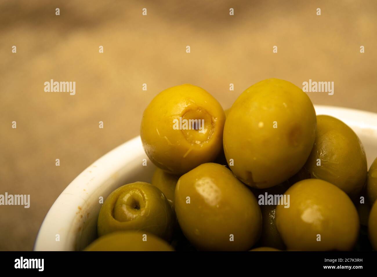 Olives vertes dans un bol en céramique sur fond de toile de fond à texture grossière. Gros plan Banque D'Images