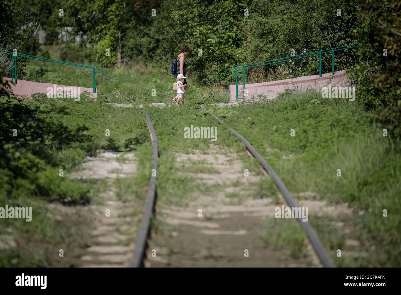 Bucarest / Roumanie - 14 juillet 2020 : une vieille femme et une petite fille marchent sur un vieux chemin de fer abandonné entre une végétation dense dans la ville. Banque D'Images