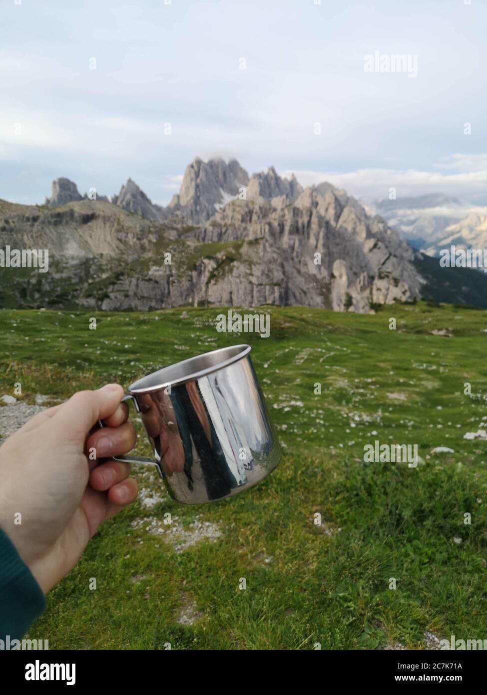 Main tient une tasse de camping, montagnes en arrière-plan Banque D'Images