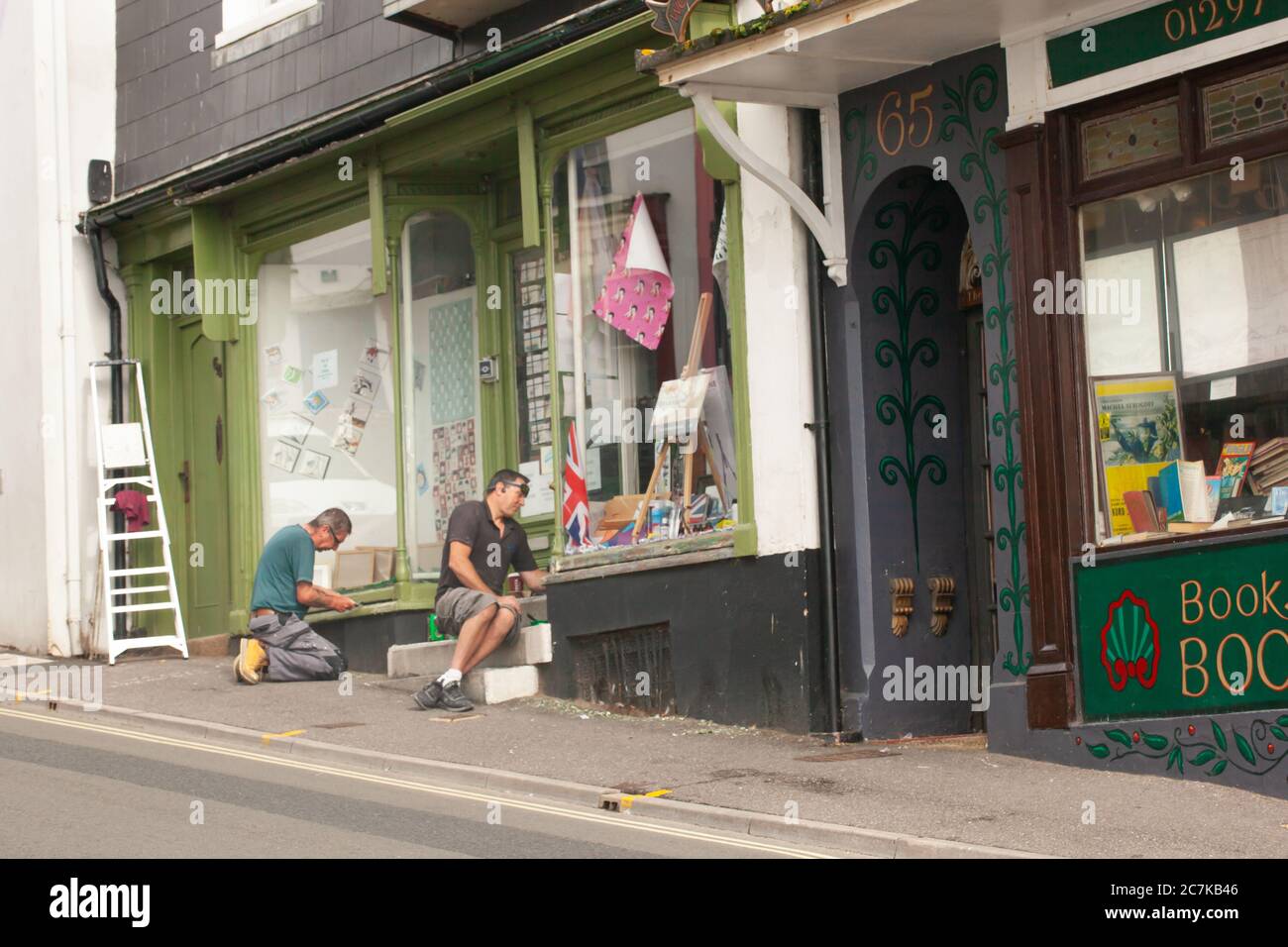 Deux hommes au travail à l'extérieur d'un magasin en préparation à la réouverture du magasin après le verrouillage Covid-19 . Lyme Regis, Grande-Bretagne Banque D'Images