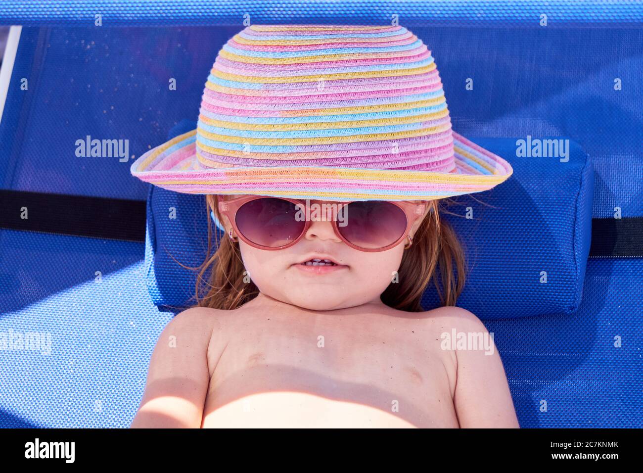 Petite fille avec lunettes de soleil et chapeau bronzage sur une chaise  longue Photo Stock - Alamy