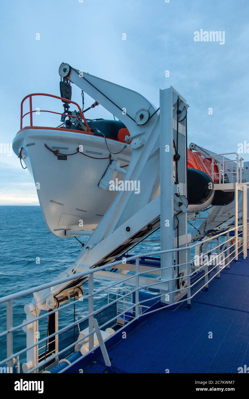 Plan vertical d'un canot de sauvetage à bord du ferry dans l'océan sous le ciel nuageux Banque D'Images