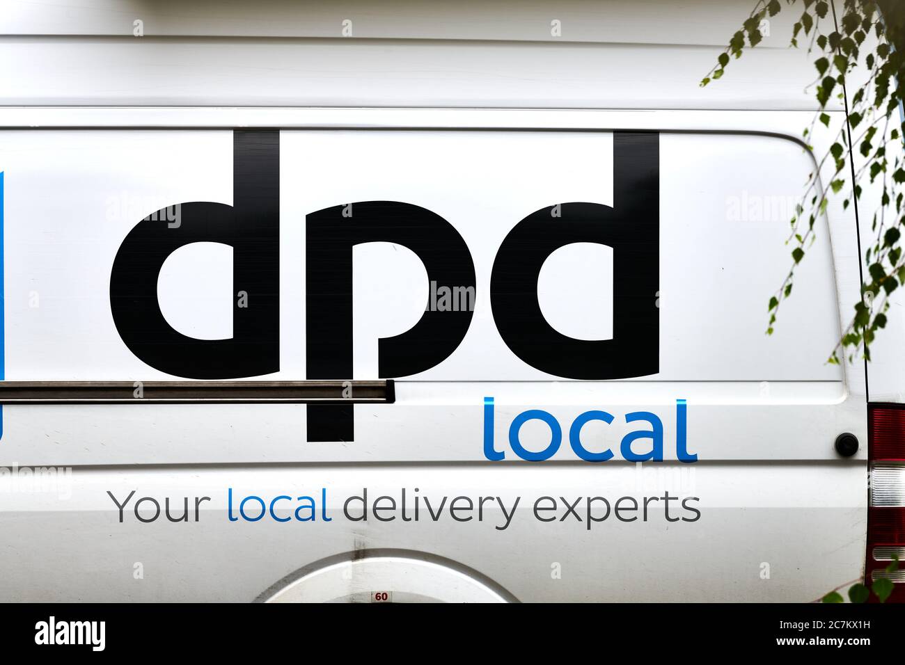 Un camion de service de messagerie blanc avec logo DPD noir s'est arrêté lorsque le conducteur livre un colis. Banque D'Images