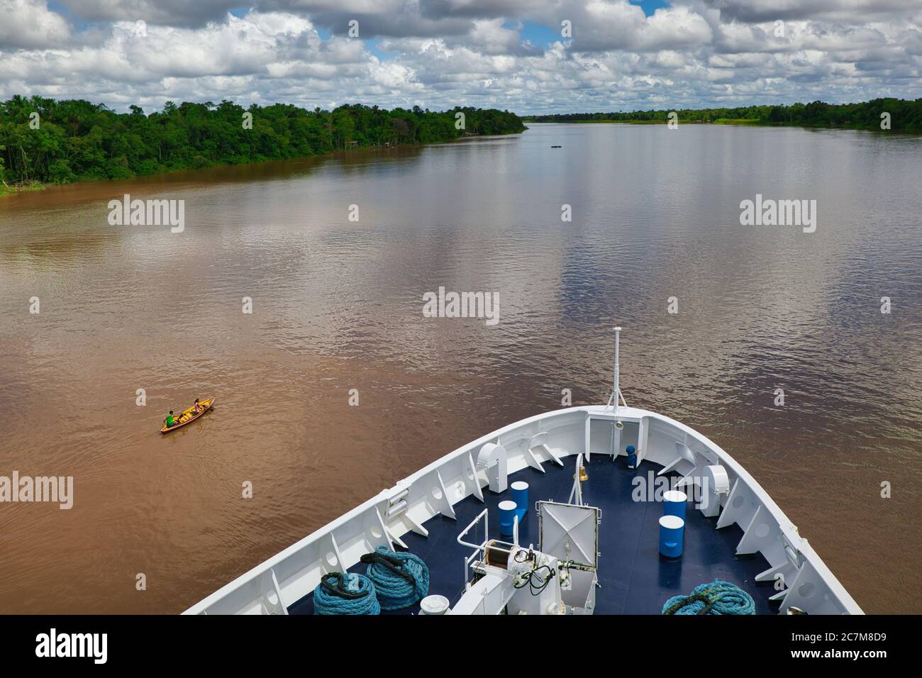 Des arceaux d'un grand navire, une vue sur la rivière Amazone devant avec les arbres et la forêt de chaque côté et les gens dans un canoë en bois à toit ouvert passant par Banque D'Images