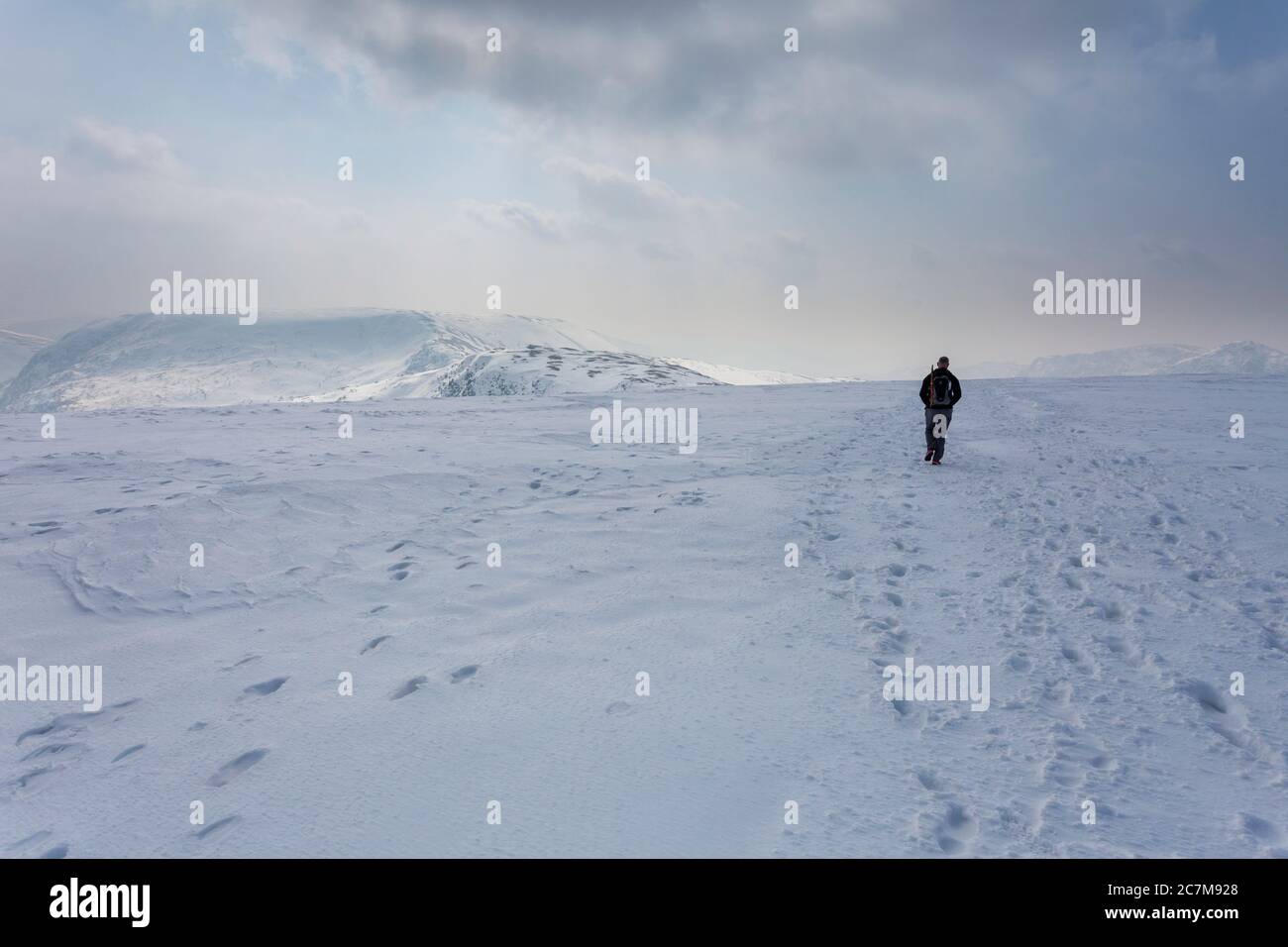 Une personne qui marche à travers une neige couverte est tombée vers Mardale Ill Bell dans le parc national de Lake District, Cumbria Banque D'Images