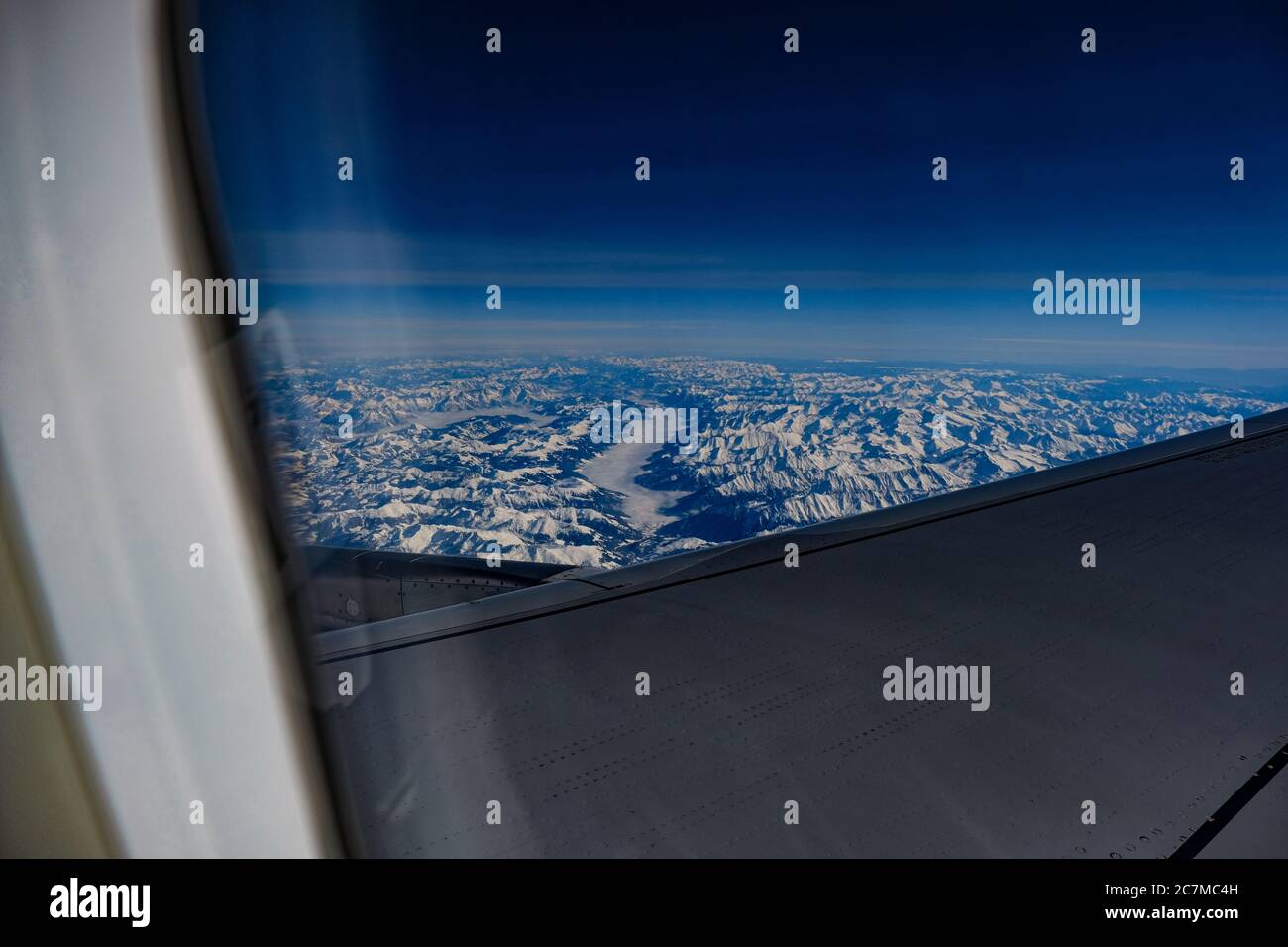 Photo des chaînes de montagnes d'une fenêtre d'avion partiellement obstruée par ailes d'avion Banque D'Images