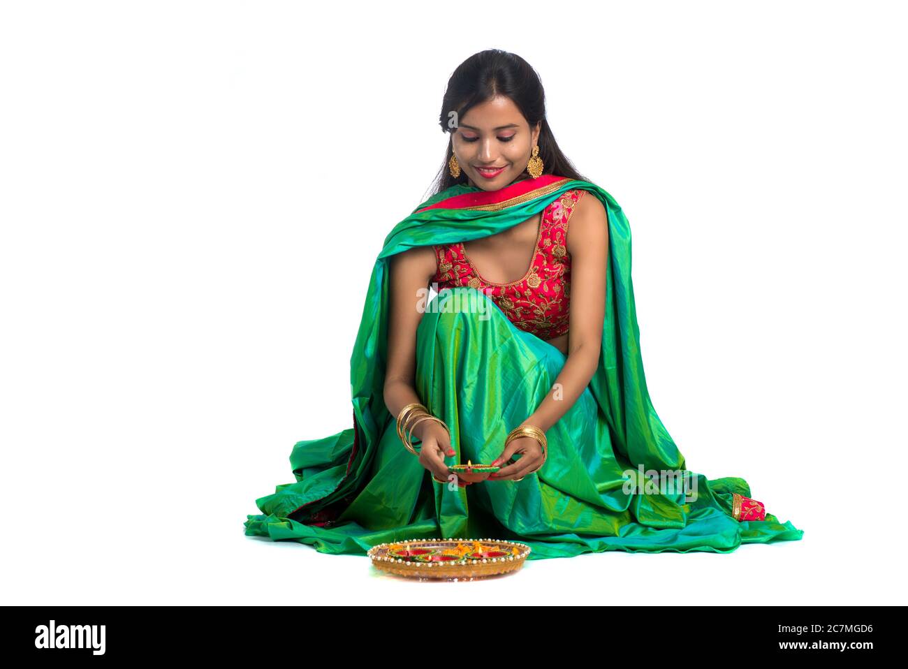 Portrait d'une fille traditionnelle indienne tenant Diya et faisant Rangoli. Fille célébrant Diwali ou Deepavali avec la tenue de lampe à huile pendant le festival de l Banque D'Images