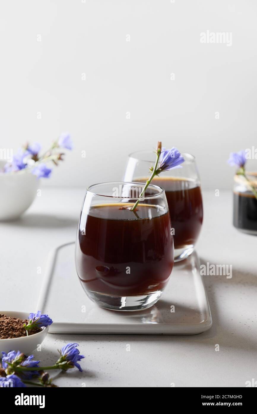 Café racine de chicorée en verres et fleurs fraîches. Avantages pour la santé. Format vertical. Banque D'Images