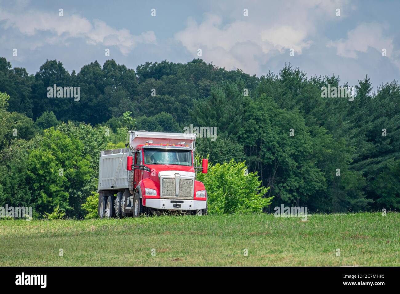 Camion-benne rouge lors d'une chaude journée d'été. La chaleur qui monte à partir de la surface de l'autoroute crée un motif ondulé et chatoyant intéressant sur le camion et l'arrière-plan. Banque D'Images