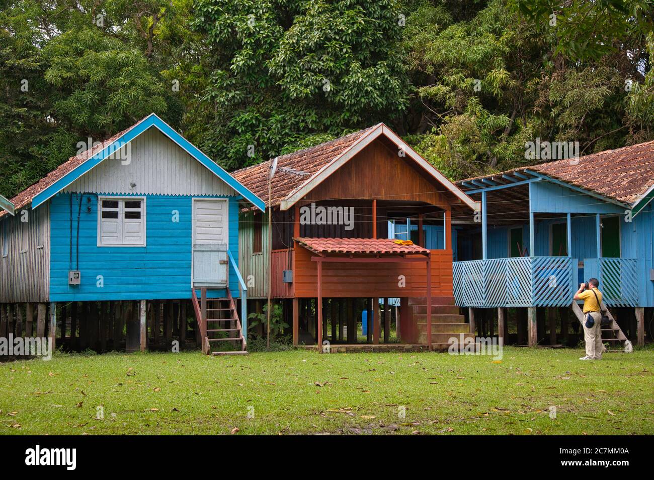 Trois huttes de village sur pilotis pour les inondations de l'Amazone, avec le visiteur prenant une photo, près de Manaus dans l'État d'Amazonas, Brésil Banque D'Images