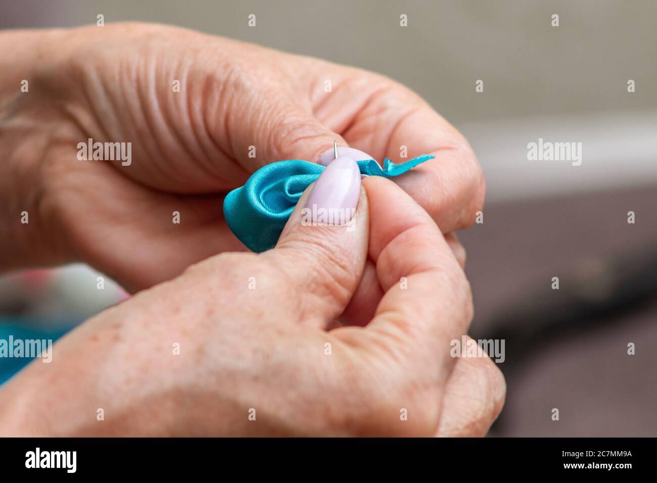 les vieilles mains de femmes cousèdes tissus avec une aiguille et un fil Banque D'Images