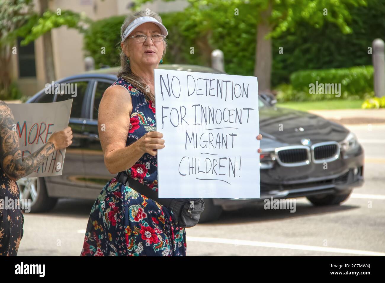 7 2 2019 Tulsa USA aucune détention pour enfants migrants innocents - femme plus âgée en jolie robe et chapeau de soleil tient signe au rallye avec voiture passant par - tatouage Banque D'Images