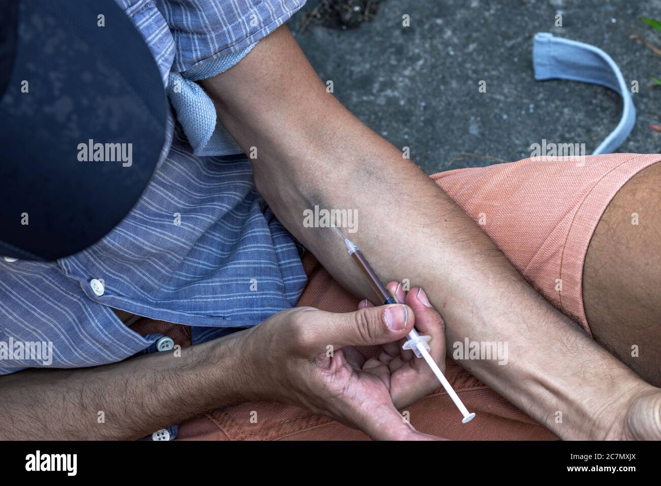 Mains d'un drogué avec une seringue pleine de stupéfiants, d'héroïne ou de cocaïne aux veines du bras. Toxicomanie et obsession. Gros plan. Banque D'Images