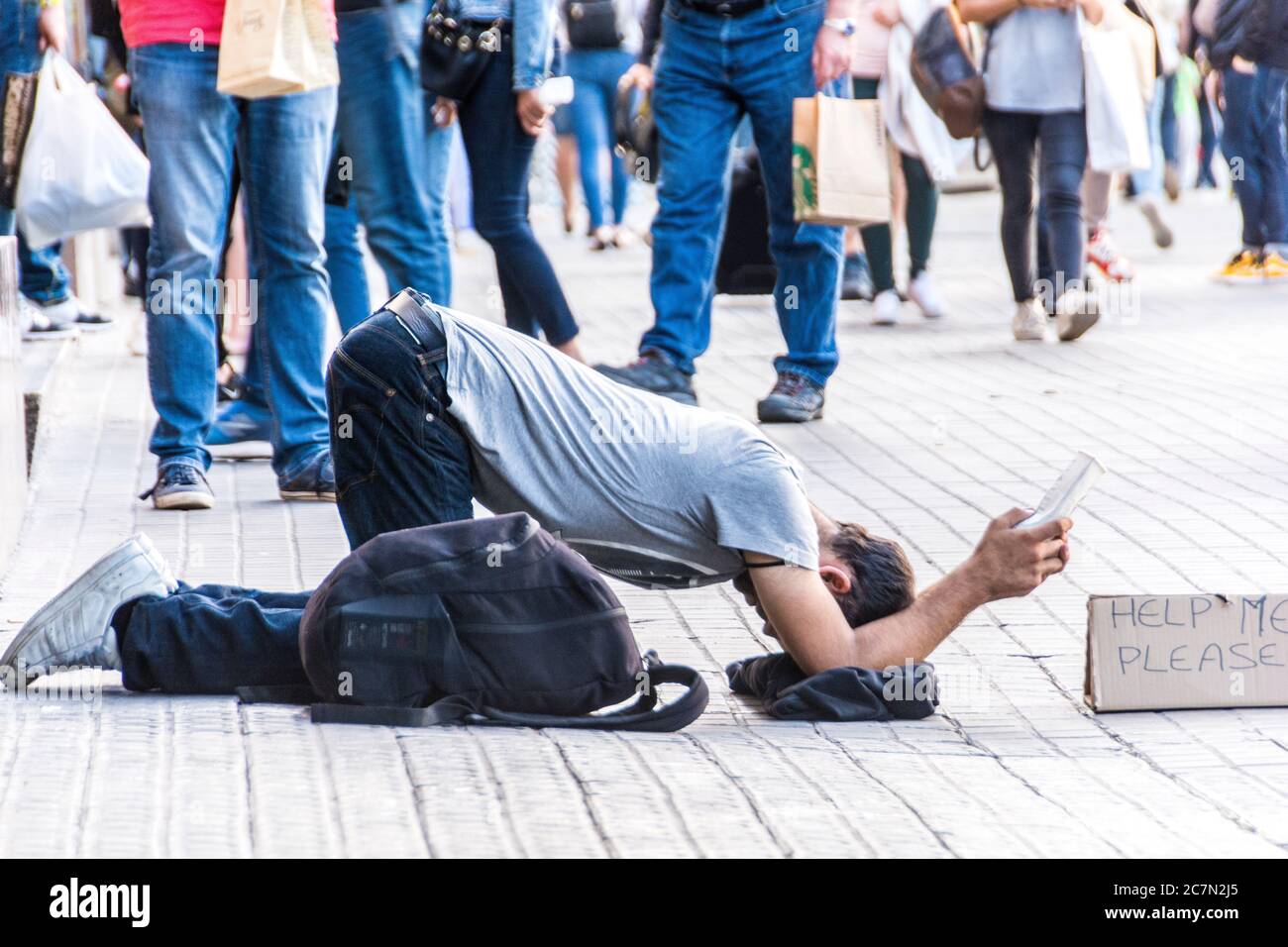 Un jeune homme sans abri avec un retour avec un panneau indiquant, 'Aidez-moi s'il vous plaît,' Barcelone, Espagne. Banque D'Images