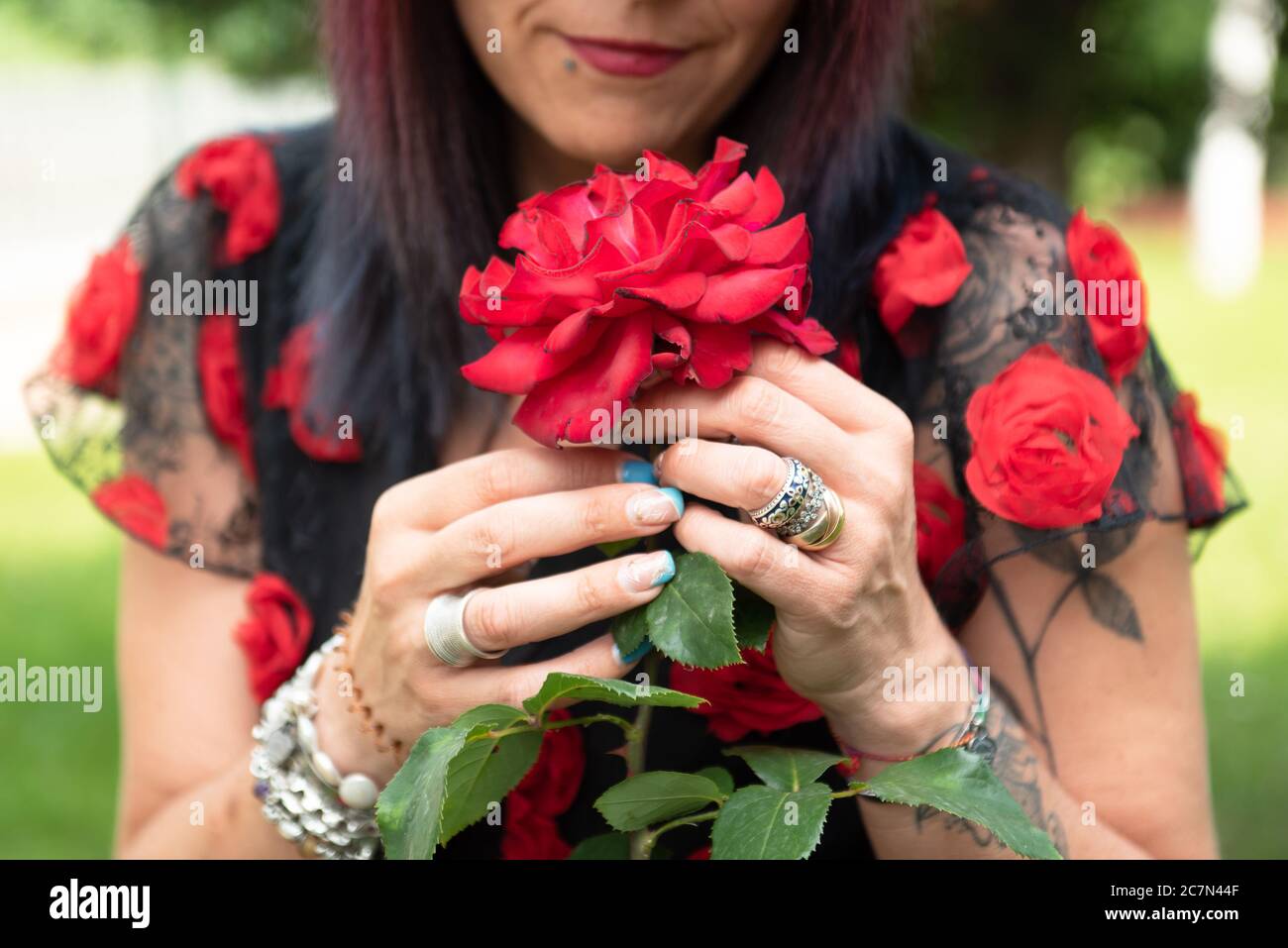 Femme snihes l'arôme de belles roses rouges dans un jardin botanique. Banque D'Images