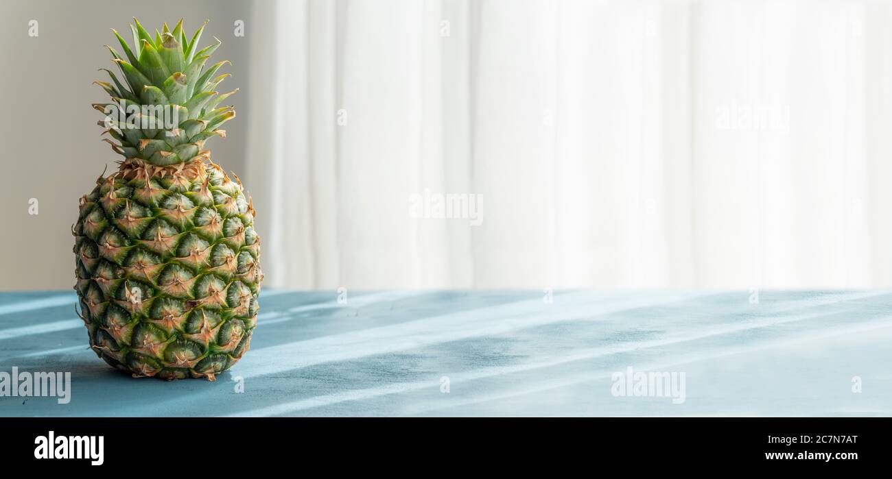 Ananas frais et biologique sur une surface en bois bleu avec une lumière naturelle et lumineuse. Banque D'Images