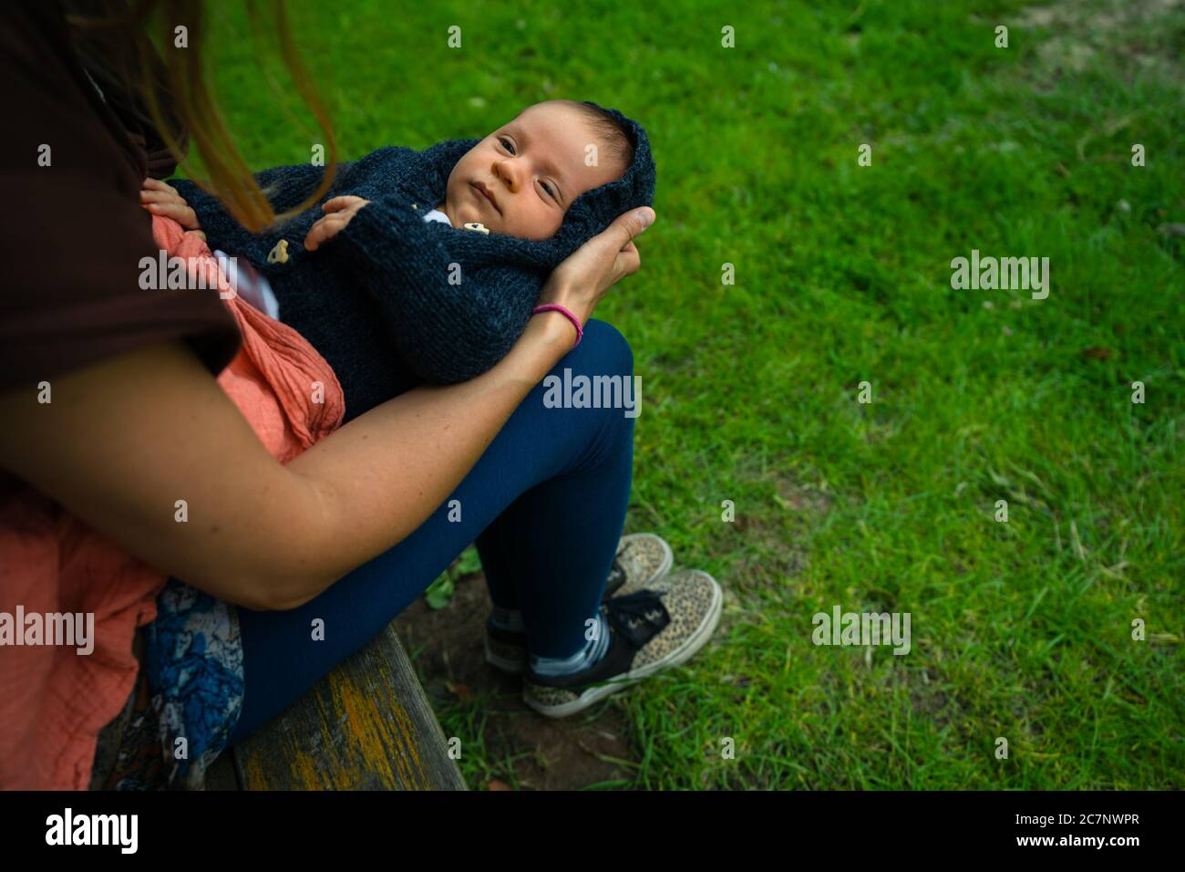 Une jeune mère se repose sur un banc de parc avec son bébé sur ses genoux Banque D'Images