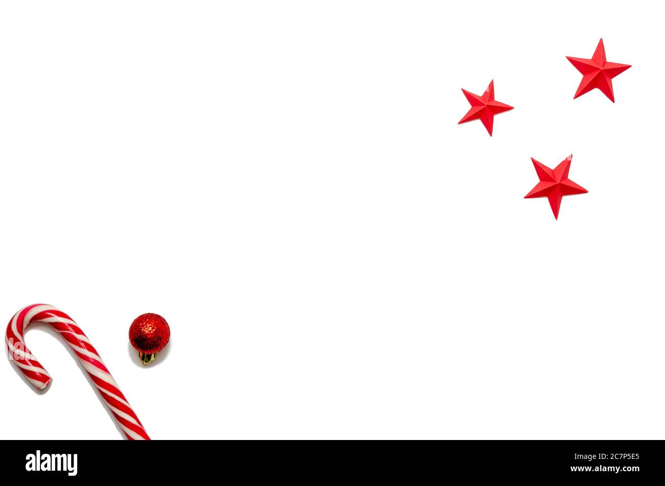 Noël et nouvel an composition minimale avec espace de copie en canne à sucre, boule de Noël rouge, étoiles sur fond blanc. Concept vacances d'hiver Banque D'Images