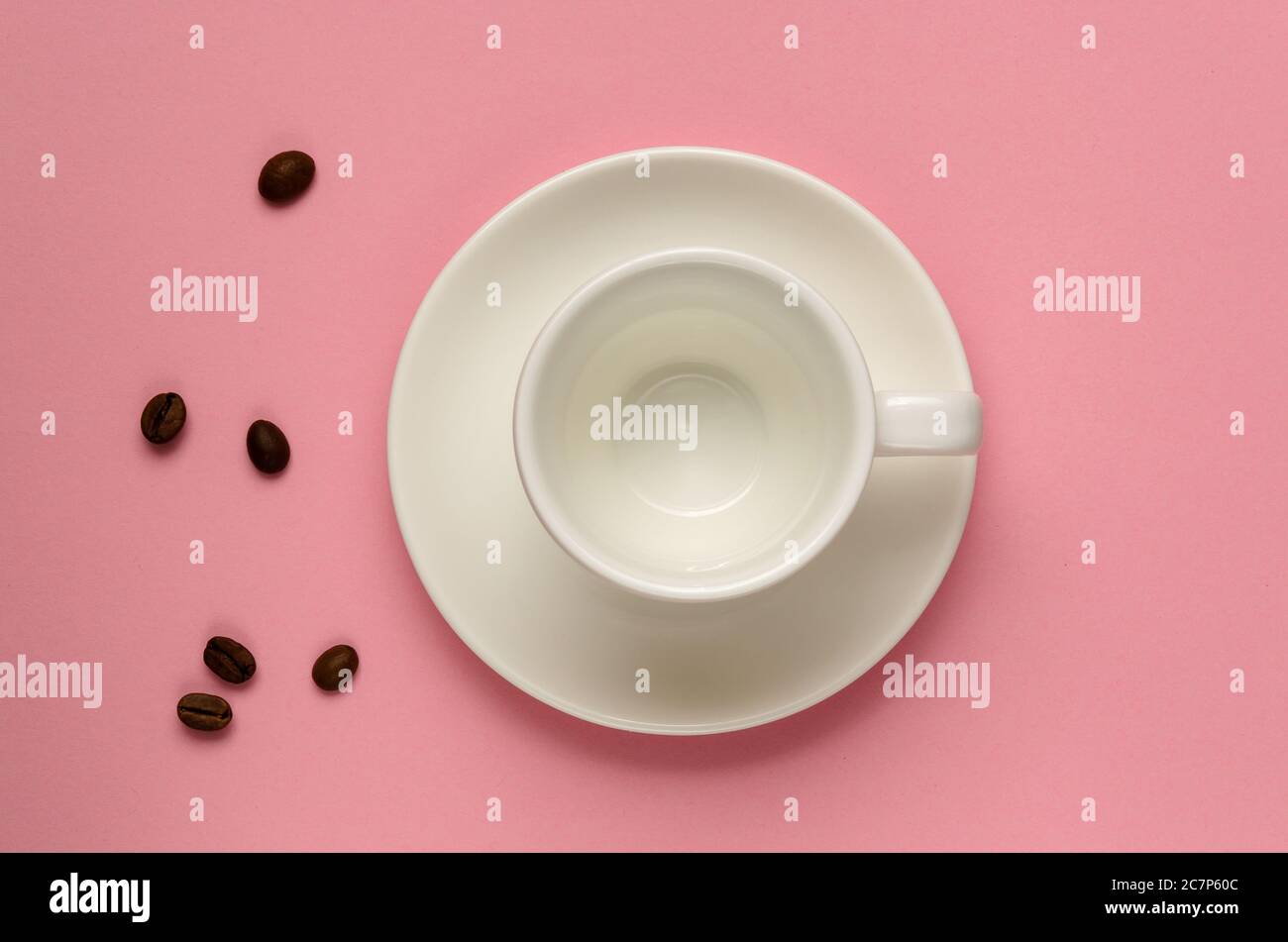 Videz la tasse à café blanc propre sur la soucoupe et quelques grains de café sur fond rose millénaire. Style minimaliste. Modèle pour blog féminin, médias sociaux Banque D'Images