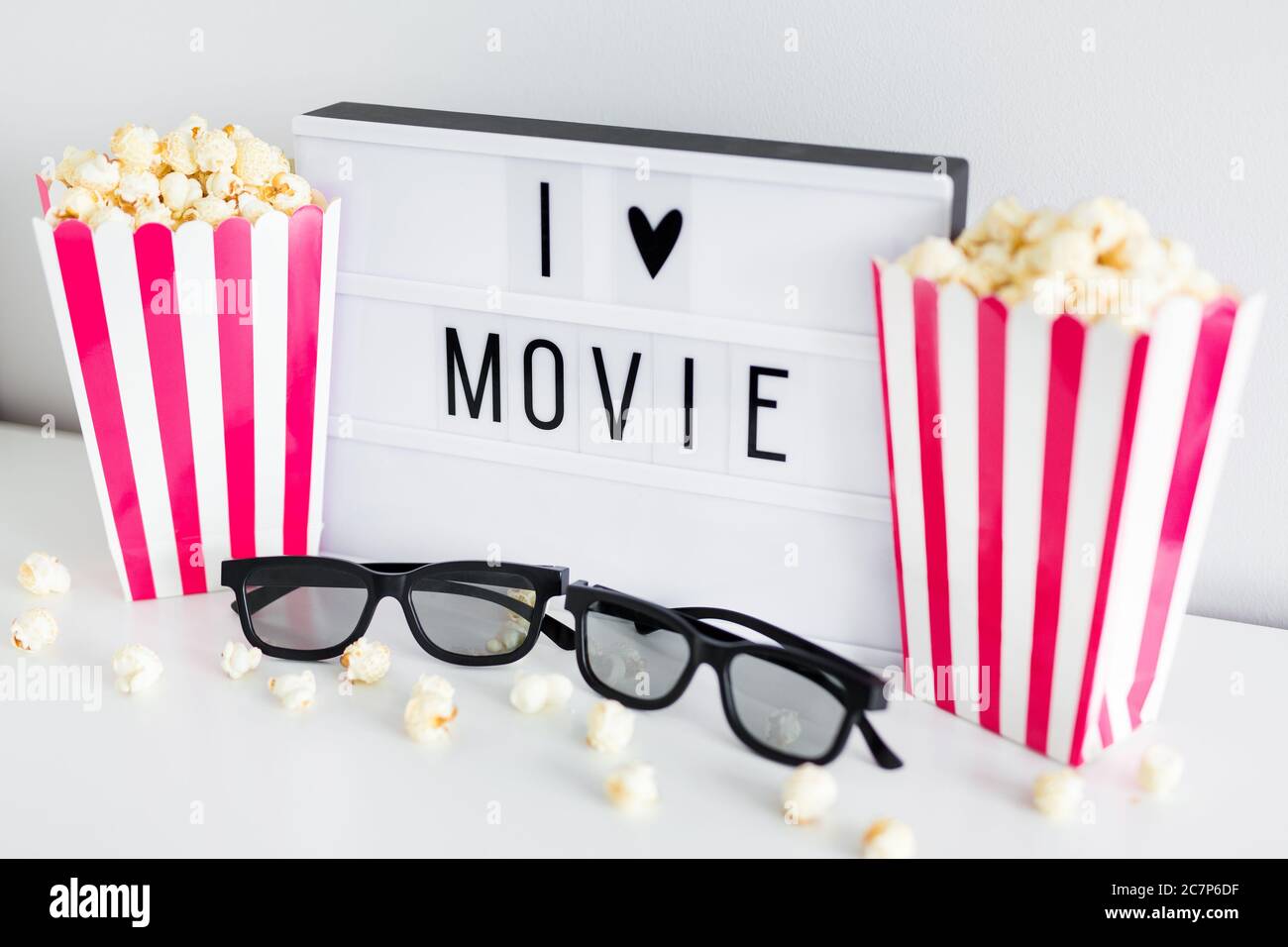 Cinema concept - gros plan des boîtes à rayures roses avec pop-corn, lunettes 3d et boîte lumineuse avec texte « I love movie » Banque D'Images