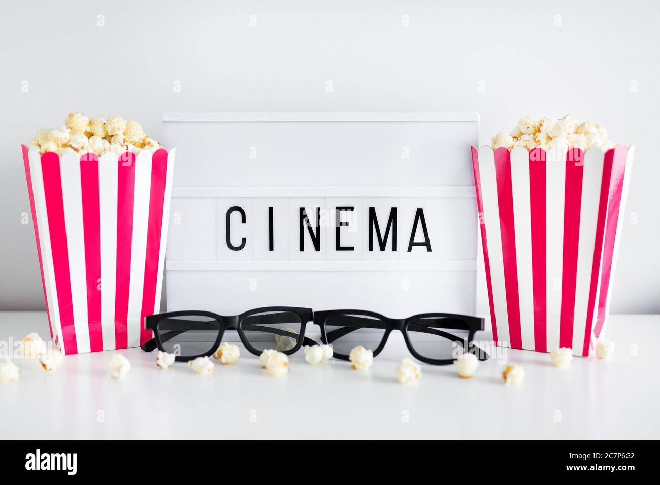 cinema concept - boîtes à rayures rouges avec pop-corn, lunettes 3d et boîte lumineuse avec mot cinéma Banque D'Images