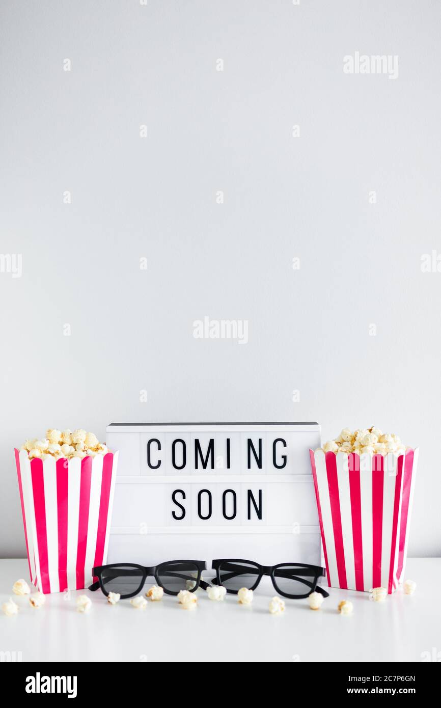 cinema concept - boîtes à rayures avec pop-corn, lunettes 3d, boîte lumineuse avec texte « bientôt disponible » et espace de copie sur fond blanc Banque D'Images