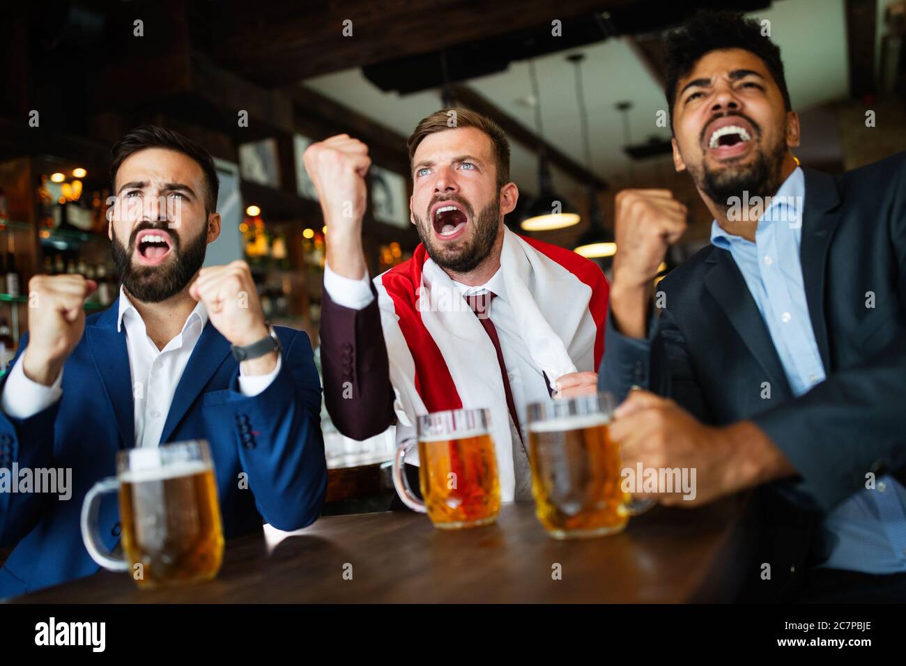 Des fans d'hommes hurlent et regardaient le football à la télévision et ...