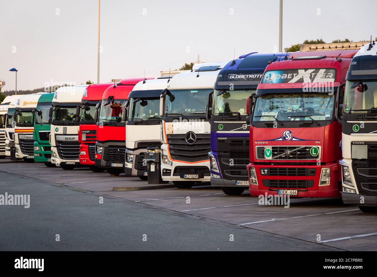 E30 HIGHWAY, ALLEMAGNE - 14 JUIN 2019 : rangée de plusieurs camions de société garés dans un parking de nuit de camions, le long de l'autoroute E30 en Allemagne. Banque D'Images