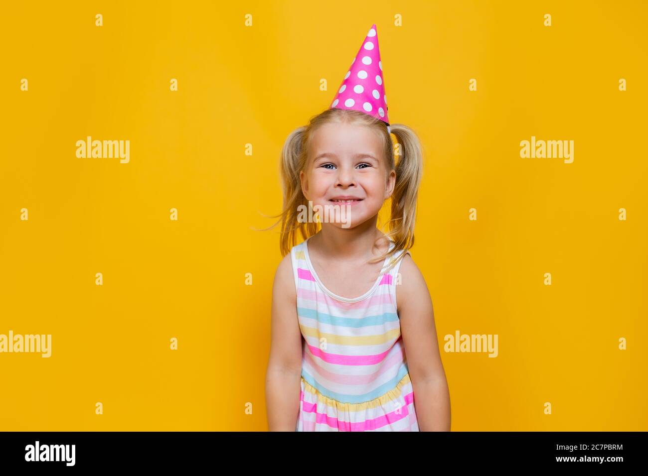 Joyeux anniversaire enfant fille avec deux contes de ponytales en capuchon rose sur fond jaune coloré. Banque D'Images