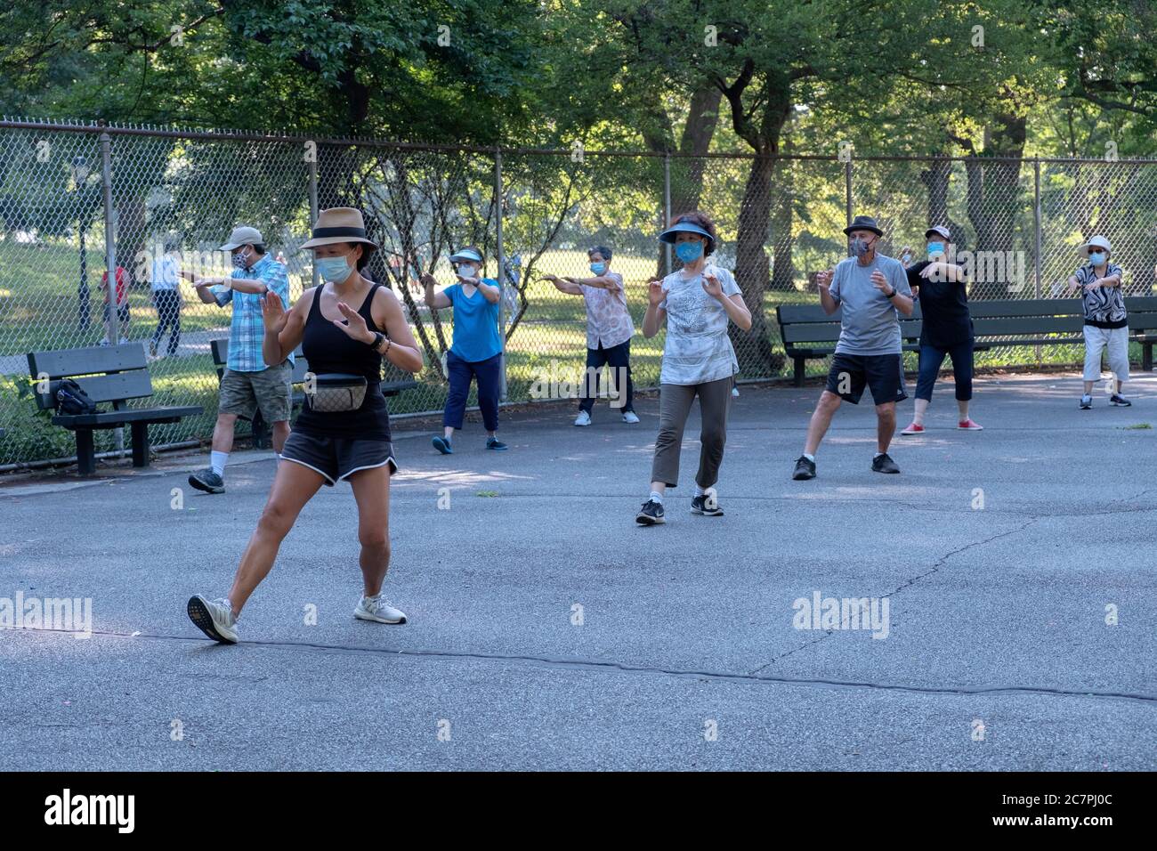 Des hommes et des femmes de divers âges et origines ethniques assistent à un cours de Tai Chi matinal, prennent des distances sociales et portent des masques chirurgicaux. Dans le Queens, New York. Banque D'Images
