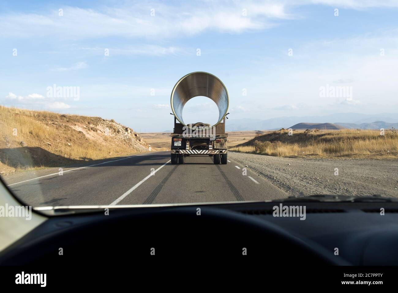 De grandes charges telles que cette section de tuyau à grand alésage se déplace sur des camions de formes et de dimensions variées autour de l'Arménie. Banque D'Images