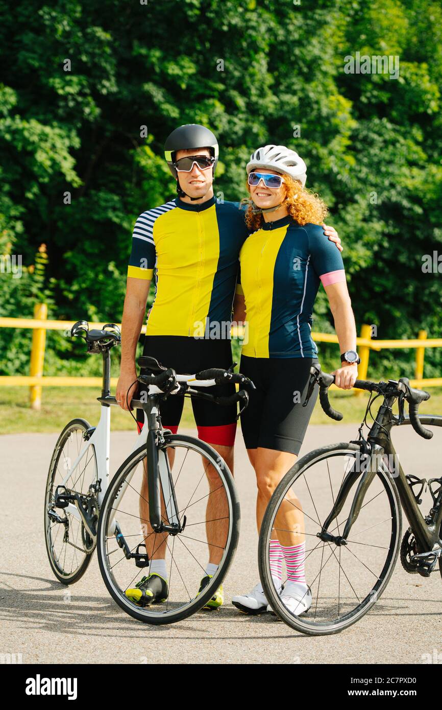 Couple cycliste mignon posant avec leurs vélos, portant les mêmes couleurs Banque D'Images