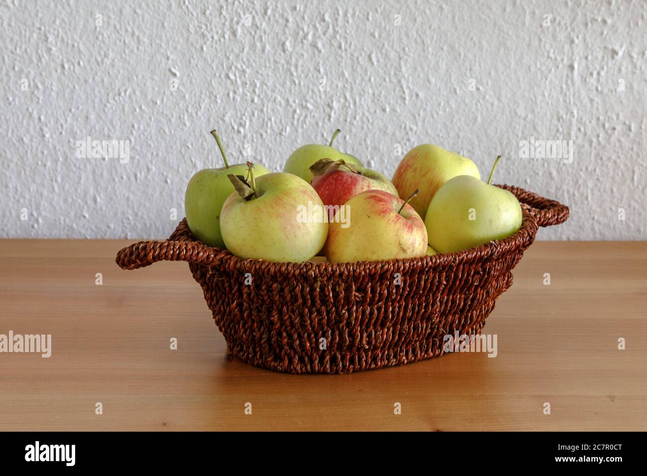 Pommes dans un petit panier sur une table en bois Banque D'Images