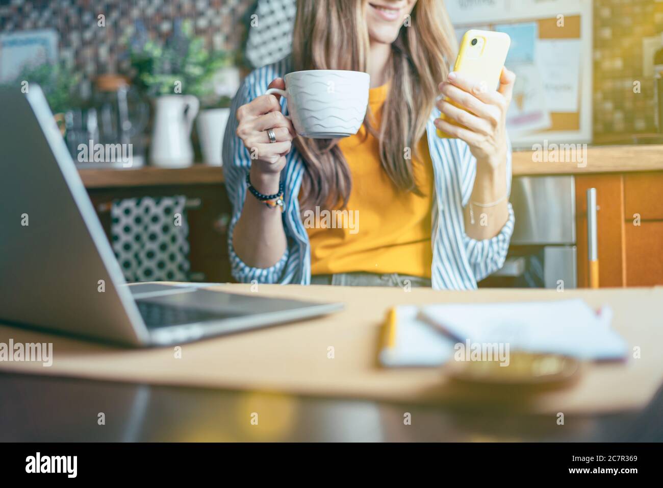 Femme d'affaires ayant un appel vidéo facetime. Une fille heureuse et souriante travaillant à domicile kithcen et buvant du café. Utilisation d'un ordinateur et d'un appareil mobile ph Banque D'Images