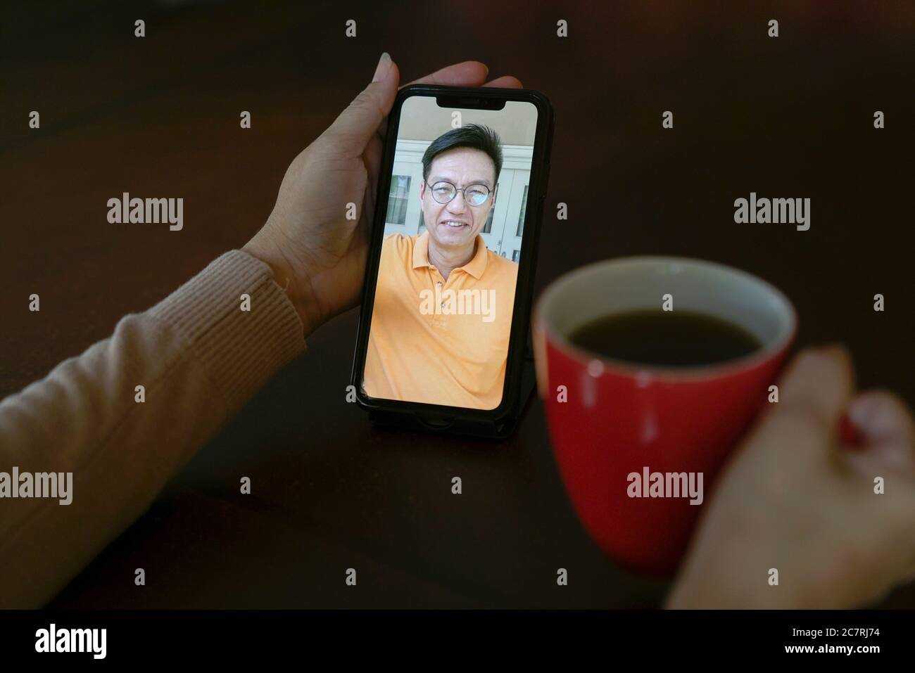 Femme avec une tasse de café ayant un appel vidéo et de discuter avec un partenaire sur le téléphone portable Banque D'Images