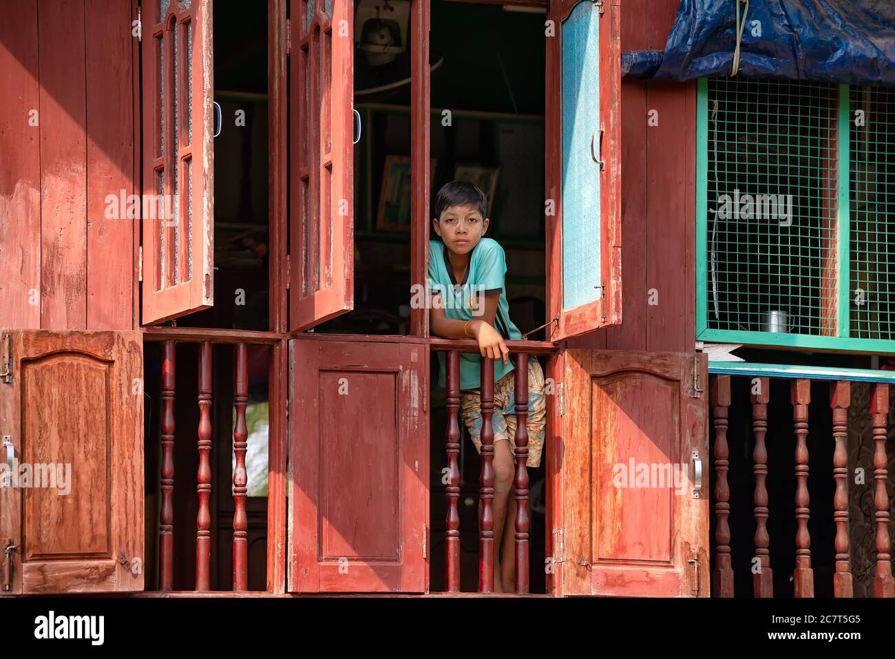 Mon State, Myanmar - 30 décembre 2019 : vue d'un jeune garçon regardant de la fenêtre de sa maison dans un village rural Banque D'Images