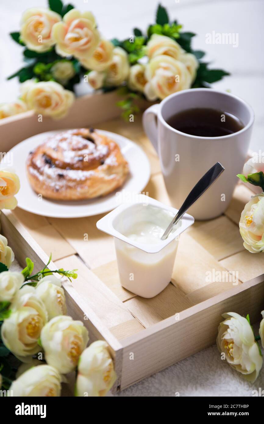 bonjour - petit déjeuner avec un pain sucré, du yaourt et du thé sur un plateau en bois Banque D'Images