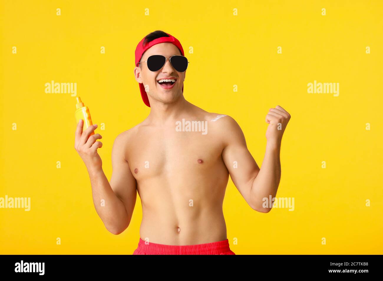 Jeune homme heureux avec crème de protection solaire sur fond de couleur Banque D'Images