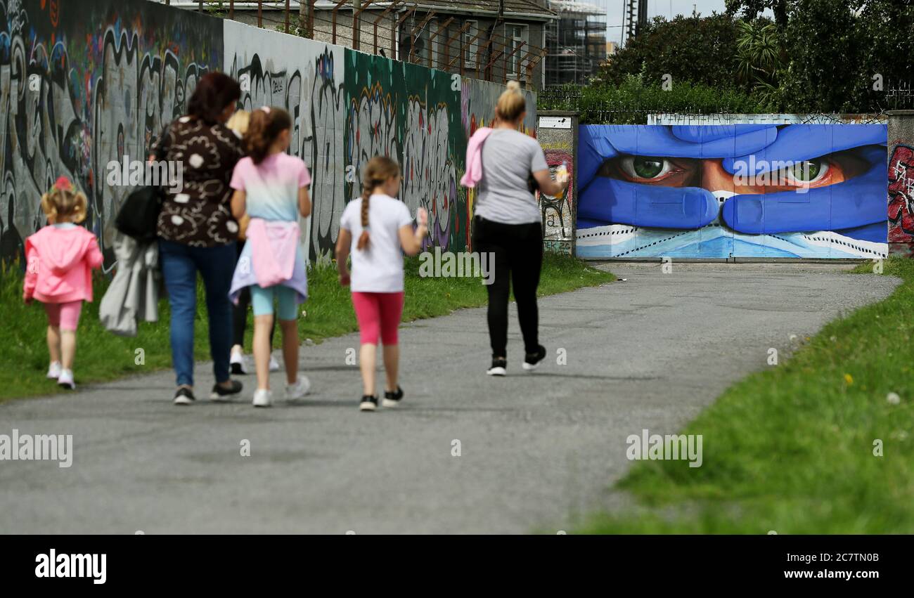 Les gens marchent devant l'artiste basé à Dublin Asbestos dernière dans sa série de portraits masque, la fresque dans le centre-ville de Dublin est intitulé 'Protégez-nous' et souligne la nécessité de porter des masques de protection dans l'effort de contrôler la propagation de Covid-19. Banque D'Images