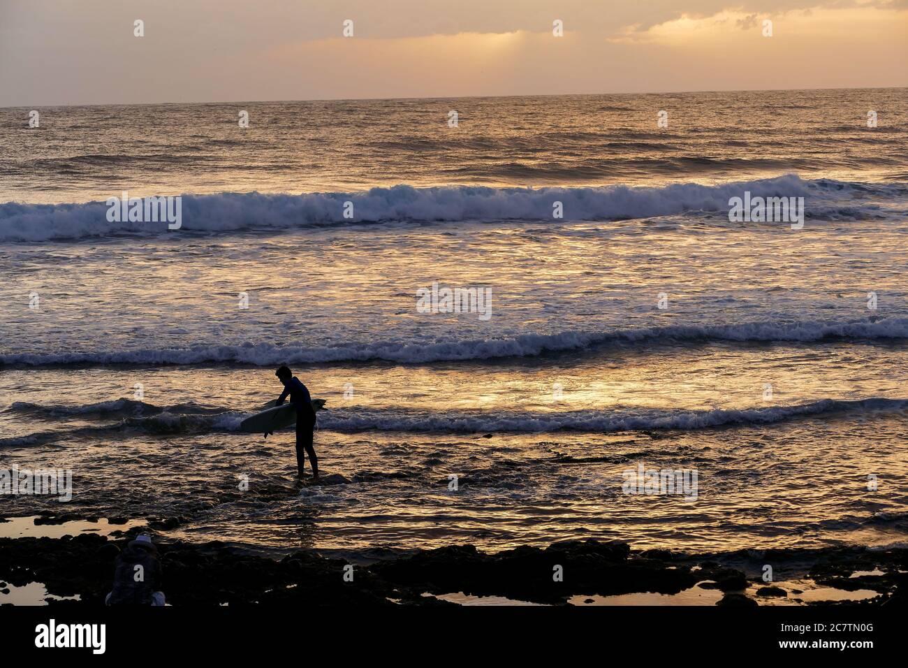 Seul un surfeur au coucher du soleil sur l'océan calme Banque D'Images