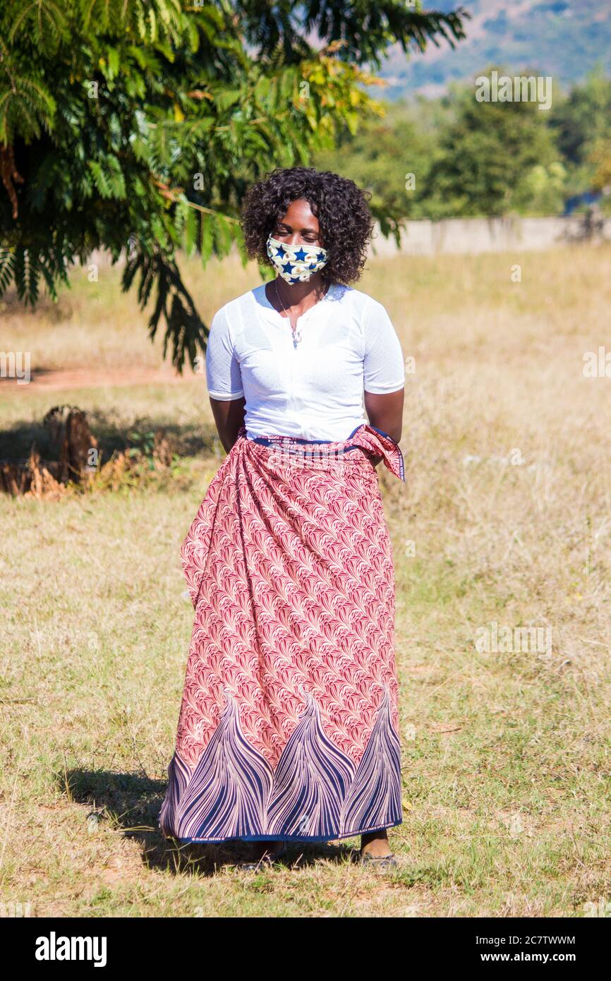 Femme portant un masque local fait main en tissu africain traditionnel sarong pour la protection contre le virus corona Banque D'Images