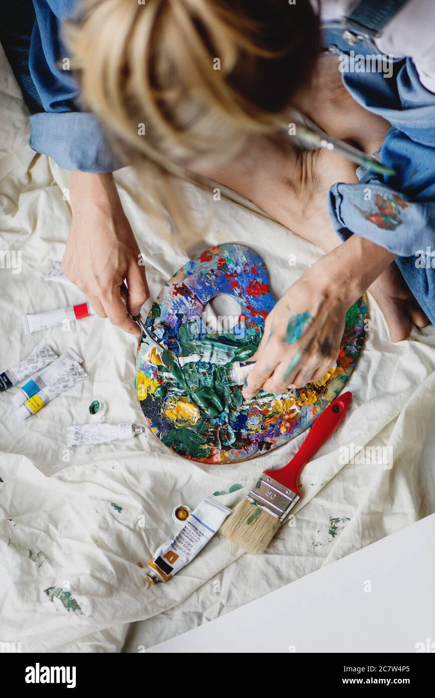 Vue de dessus d'une artiste féminine mélangeant différentes peintures sur la palette. Banque D'Images
