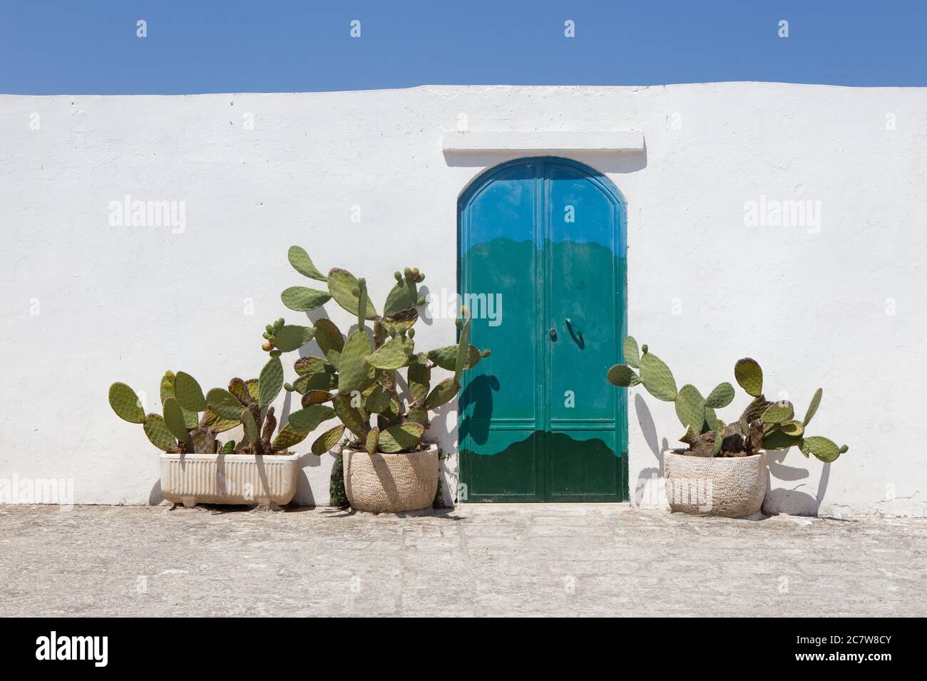 Photo au niveau des yeux d'une porte en dégradé sur un mur blanc à côté des  plantes de cactus à Santorini, Grèce Photo Stock - Alamy