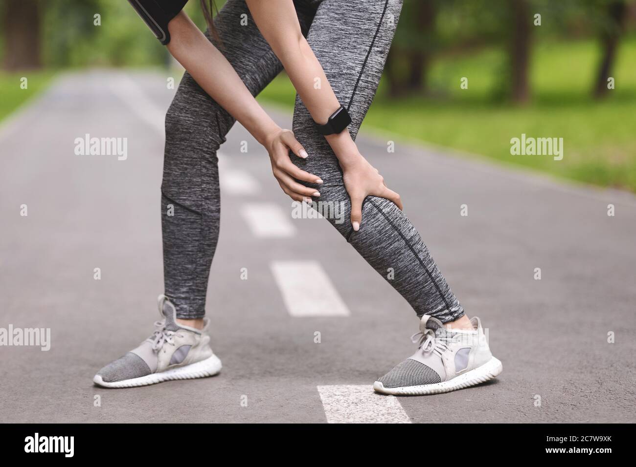 Lésion du mollet. Femme sportive massant la jambe, ayant des douleurs musculaires après le jogging à l'extérieur Banque D'Images