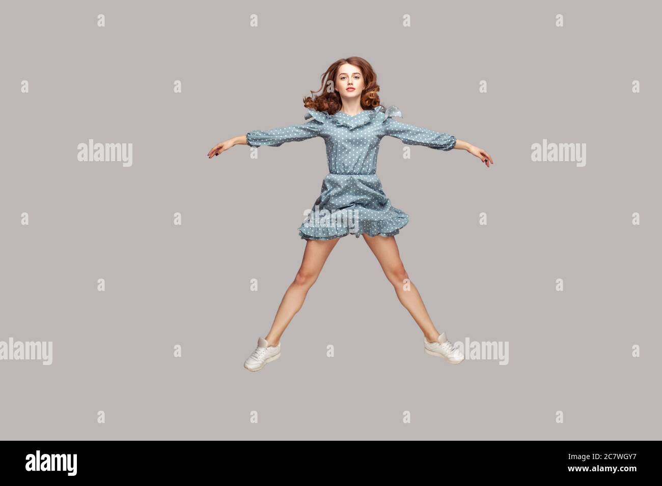 Pleine longueur fille vintage robe à volant lévitant planant en vol stationnaire dans l'air, écartez les mains jambes comme une étoile, sautant trampoline, volant et regardant venu Banque D'Images