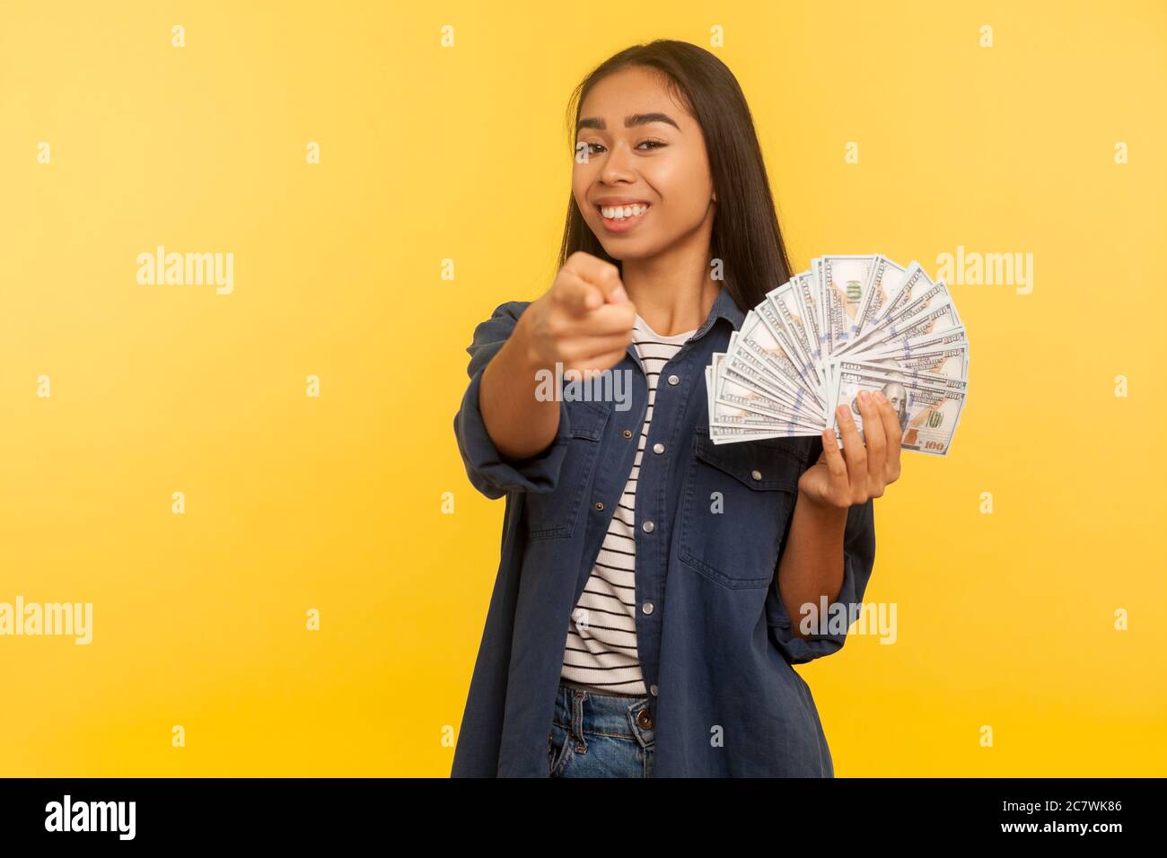 Hé, vous voulez de gros profits? Portrait de la riche heureuse femme satisfaite tenant des billets de banque en dollars et pointant vers l'appareil photo, en souriant offrant de faire de l'argent. indo Banque D'Images